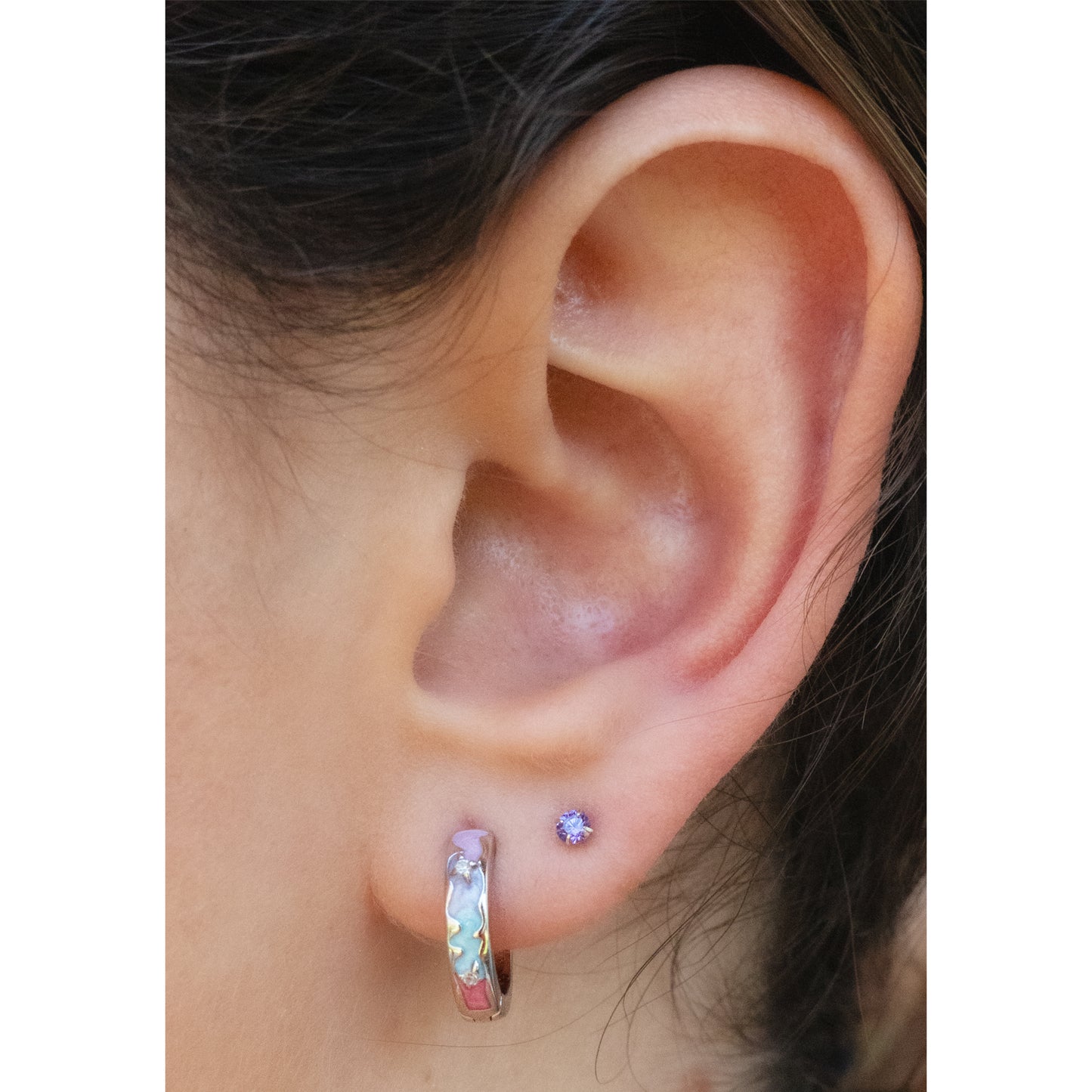 Primer plano de reja con argolla de plata de14 mm con circones blancos y esmalte de colores pasteles