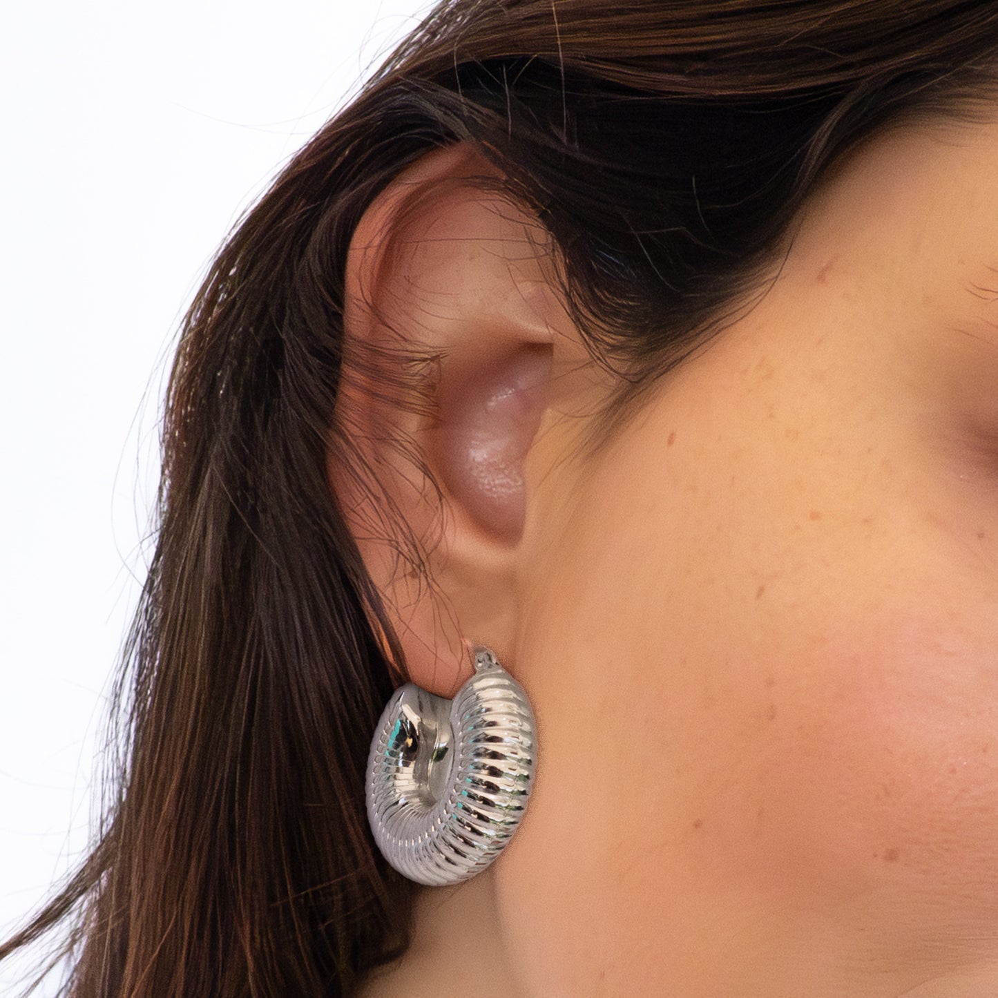 Oreja con pendiente grueso plateado de diseño acanalado.