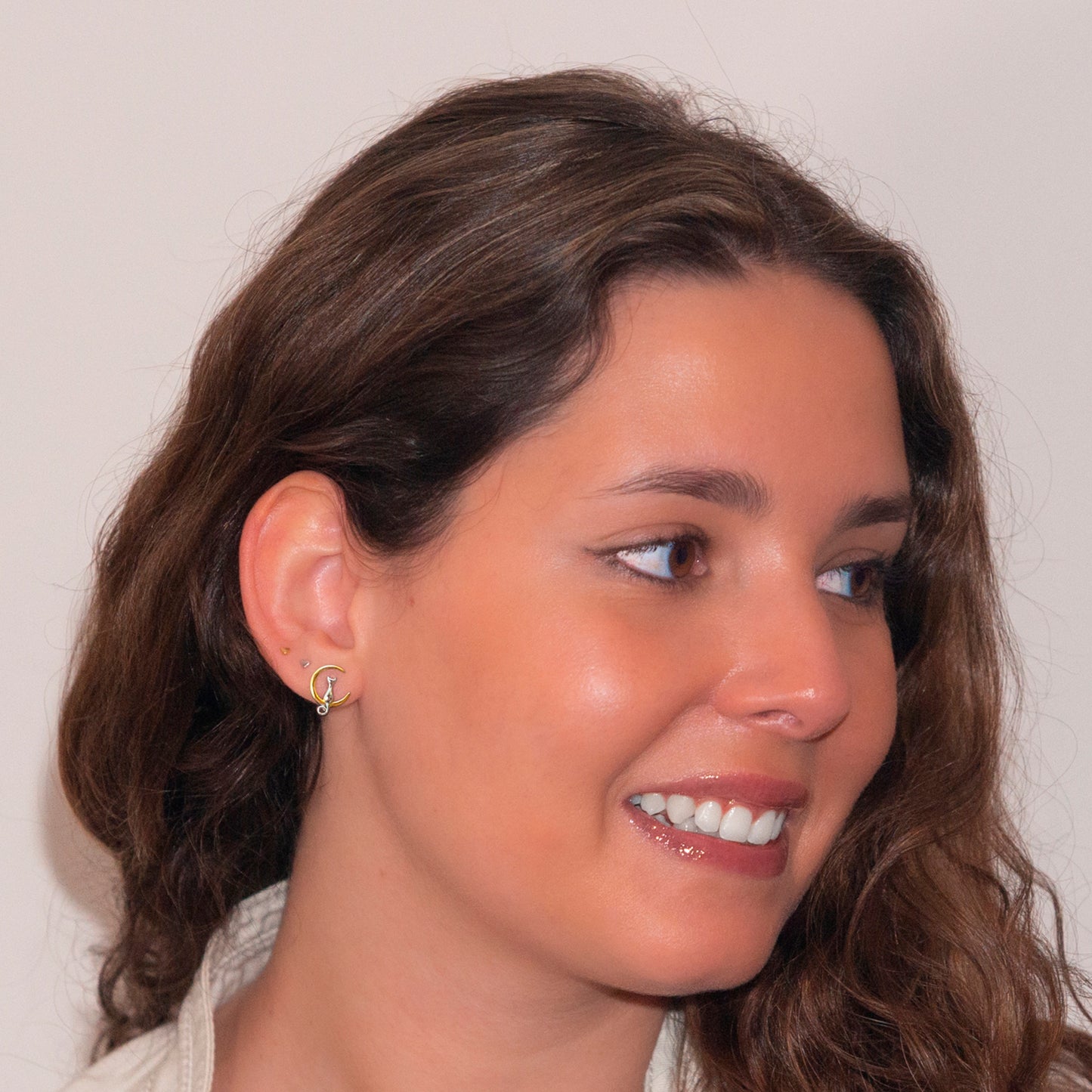 Modelo de cabello castaño sonriendo y luciendo aros de 13,1 mm, en plata 925 con de gatito plateado sentado en luna dorada