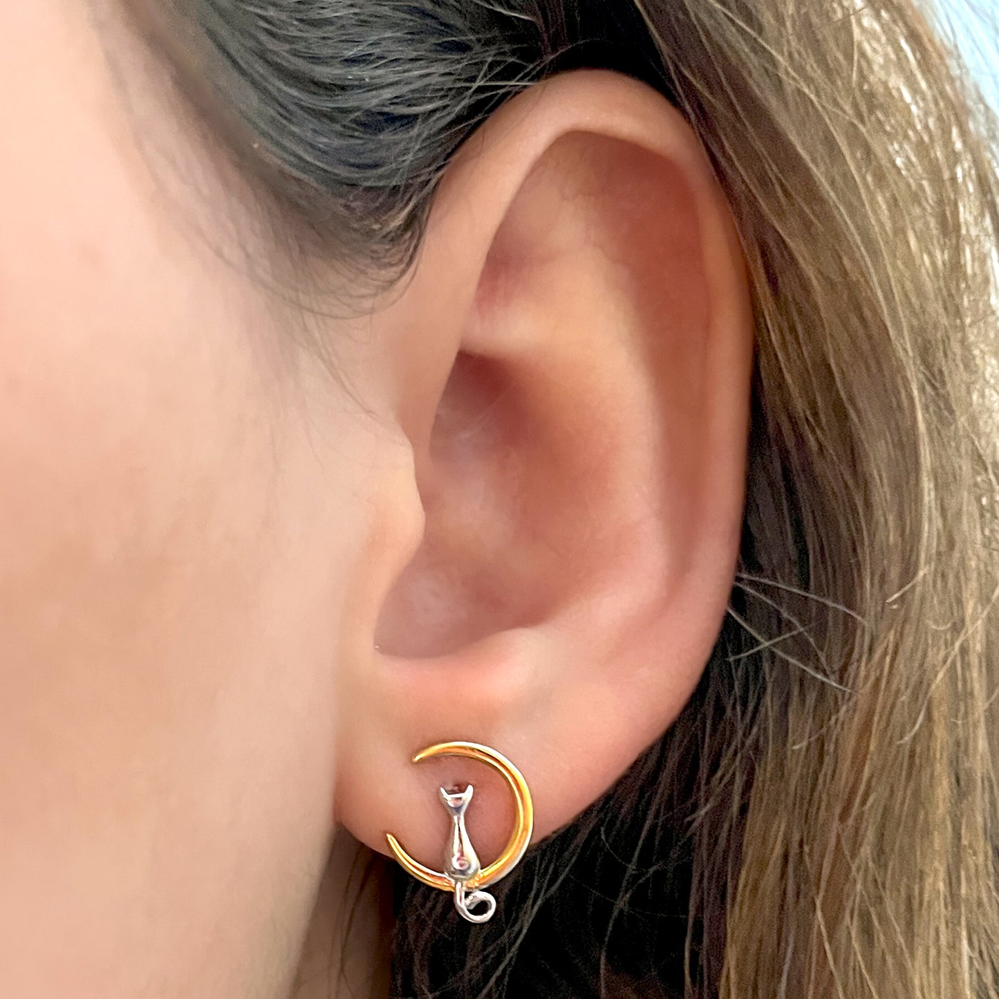 Primer plano de oreja con aros de 13,1 mm, en plata 925 con de gatito plateado sentado en luna dorada