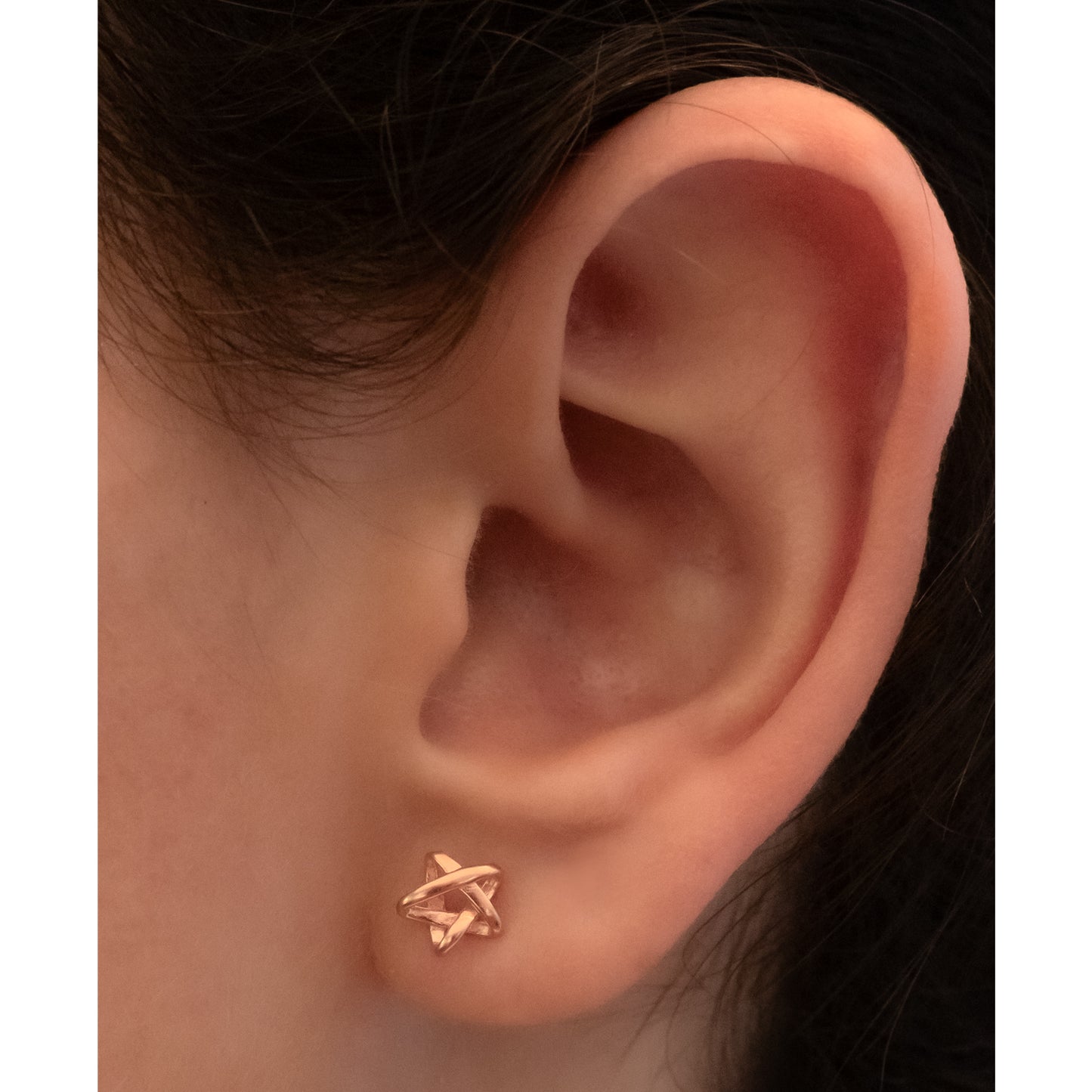 Primer plano de oreja con pendiente rose gold en forma de estrella