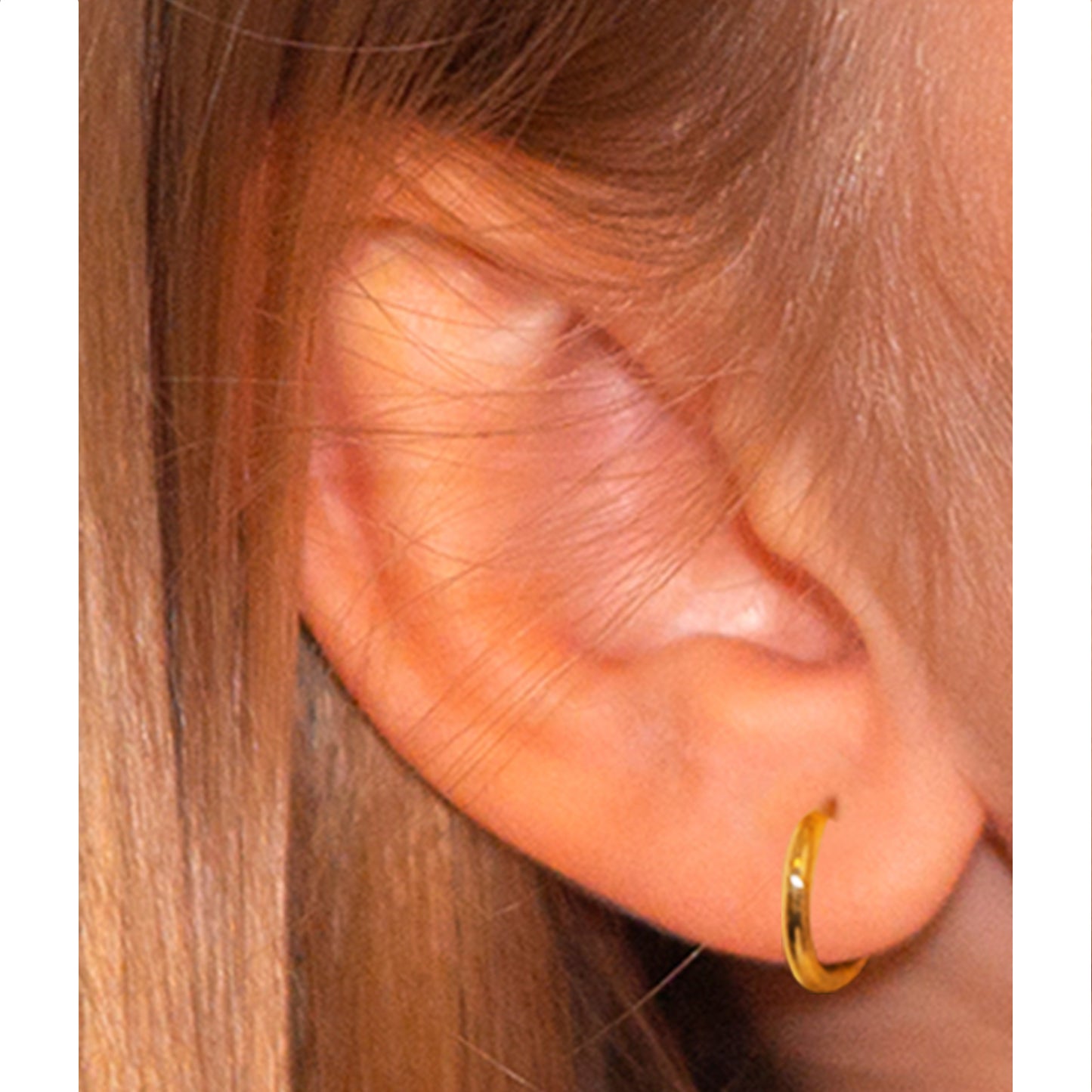 Oreja con pendiente de argollita dorada de 10 mm.
