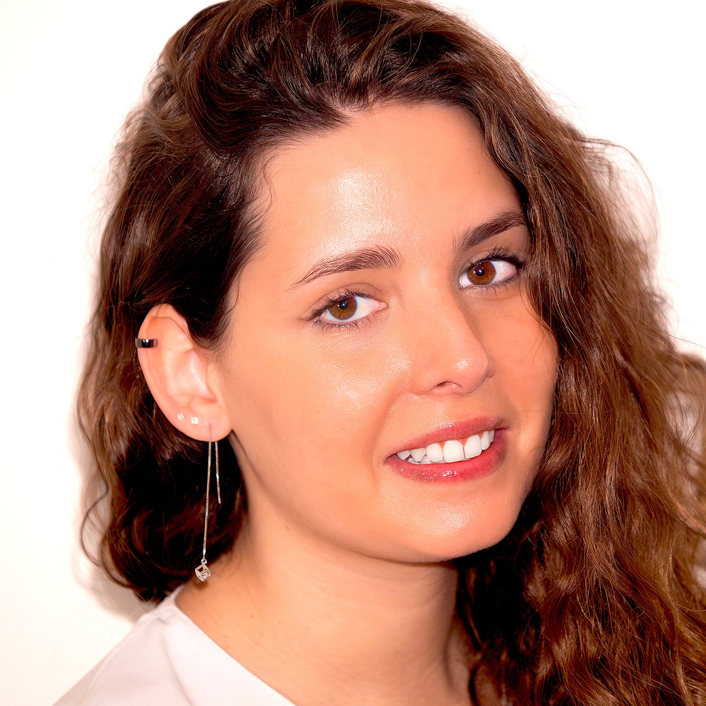 Mujer de cabello rizado usando pendientes de cubo abierto y circones en su interior.