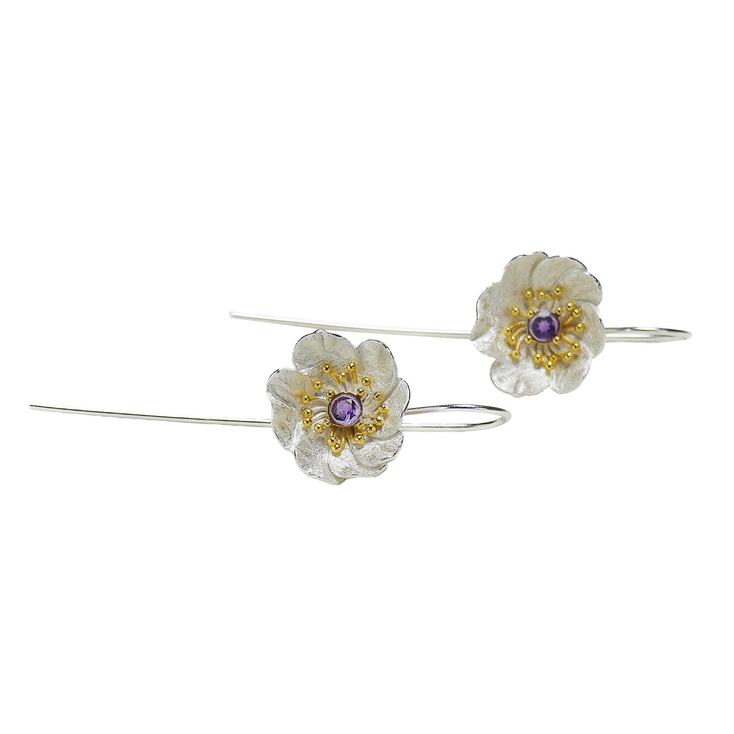Par de aros de flores con circón morado sobre fondo blanco.