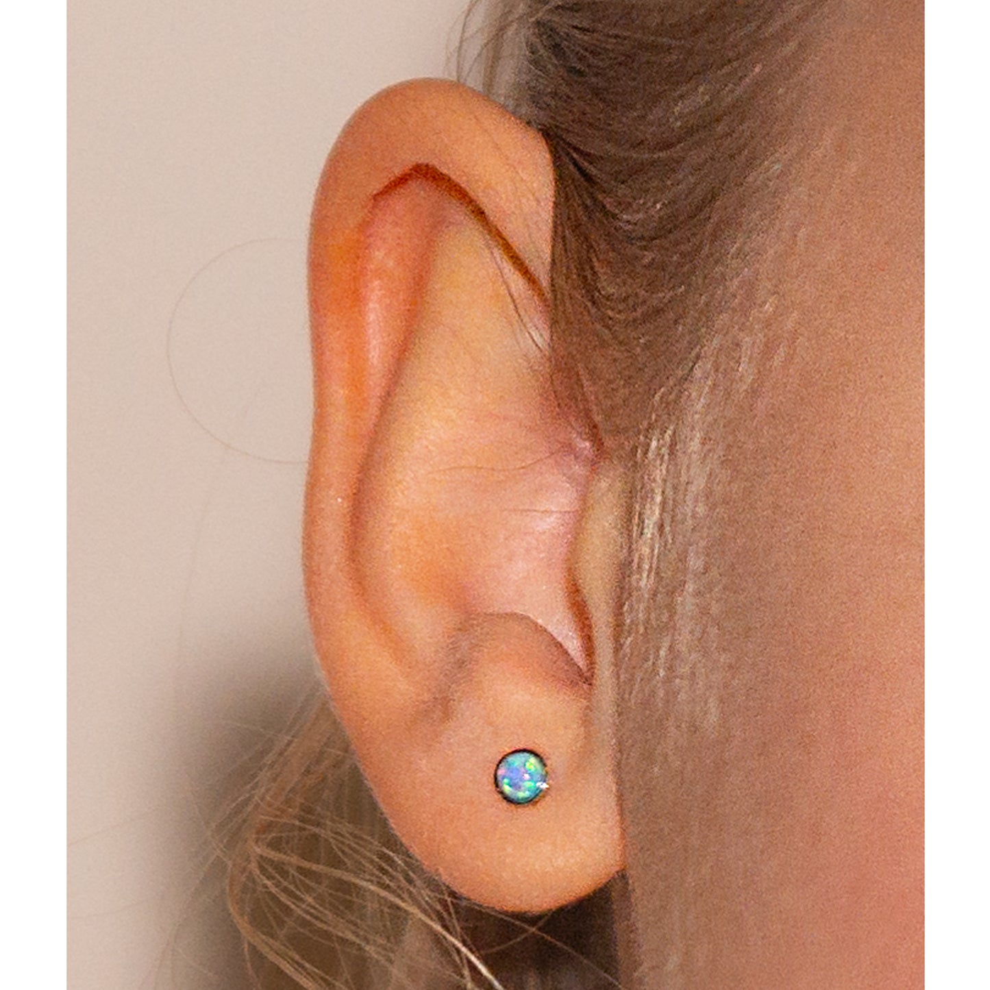 Primer plano de oreja con aritos de ópalo azul