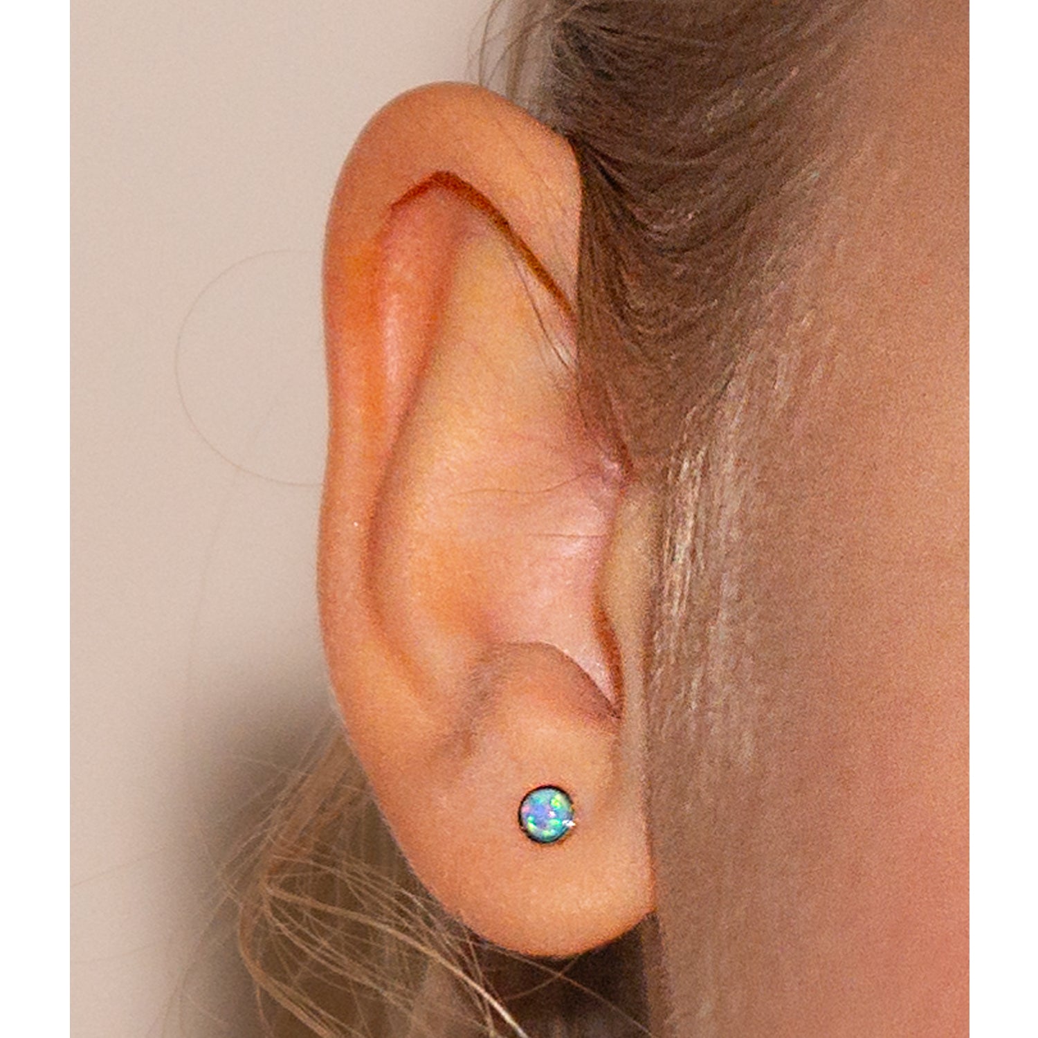 Primer plano de oreja con aritos de ópalo azul