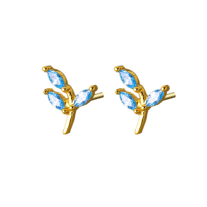 Par de aros de plata bañados en oro, en forma de ramita con hojas formadas por circones azules sobre fondo blanco